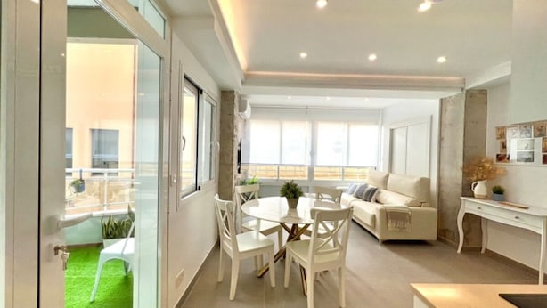 A modern living room with a dining area, a sofa, and a kitchen area with a white countertop and cabinets. - Bright apartment at Malagueta beach with private terrace (Málaga)