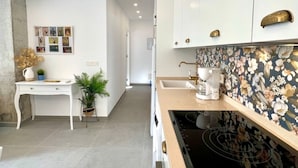 A modern kitchen with white cabinets, a coffee maker, and a floral backsplash. - Bright apartment at Malagueta beach with private terrace (Málaga)
