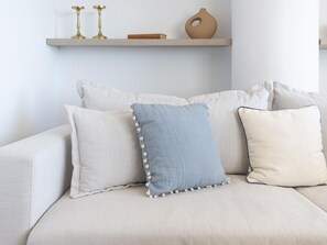 Ein Sofa mit drei Kissen, ein Regal mit Dekoration und eine Vase.