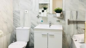 Et badeværelse med toilet, vask og spejl. Der er håndklæder på bordet.