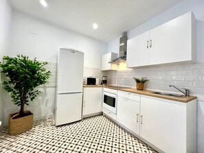 Une cuisine moderne avec des meubles blancs, un four encastré, un four à micro-ondes et un évier.
