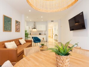 Un salon moderne avec un canapé marron, une table à manger en bois et un téléviseur fixé au mur.