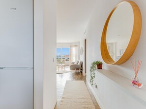 A modern interior with a hallway leading to a dining area, a large mirror, and a view of the city. - Torremolinos: Family relaxation with a lovely terrace. (Torremolinos)