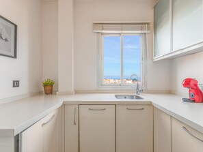 A kitchen with a window, a sink, cabinets, and a red appliance. - Torremolinos: Family relaxation with a lovely terrace. (Torremolinos)