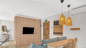 Una sala de estar moderna con un sofá, una mesa de comedor de madera y un televisor montado en la pared.