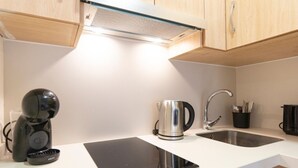 Uma cozinha moderna com uma placa de indução embutida, chaleira e máquina de café.