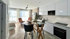 Una cucina moderna con mobili bianchi, un tavolo da pranzo in vetro e due sedie.