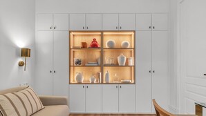 A modern living room with a beige sofa, a wooden coffee table, and a white cabinet with glass doors displaying decorative items. - Exclusive Apartment in Malaga, Near Beach (Málaga)