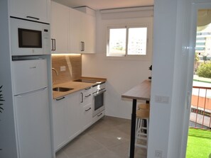 A compact kitchen with white cabinetry, a built-in oven, a microwave, and a window providing natural light. - Tranquil family home in Fuengirola (Fuengirola)