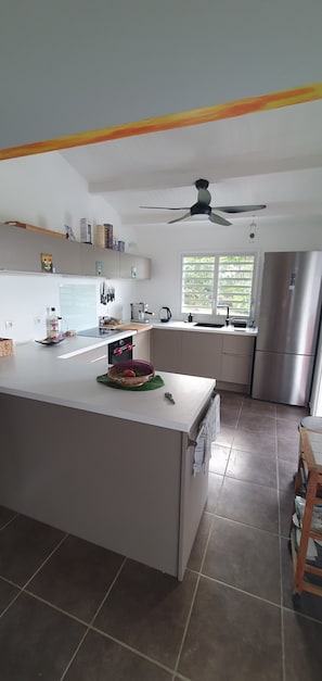 A modern kitchen with a central island, a built-in oven, and a stainless steel refrigerator. - Villa Melodie a grande Anse Deshaies (Deshaies)