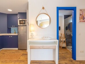 A modern kitchen with blue cabinets, a white countertop, and a round mirror above the sink. - Comfortable and well-located apartment in Málaga (Málaga)