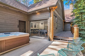 A wooden house with a hot tub, outdoor seating, and a covered deck.