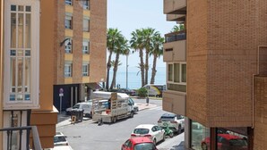 A street view with parked cars, a moving truck, and a building with a brick facade. - Coastal apartment in Málaga, near the beach, 2 bedrooms (Málaga)