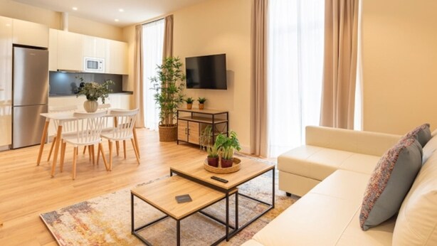 A modern living room with a sofa, coffee table, and a TV. There is a dining area with chairs and a table, and a kitchen with appliances. - Coastal apartment in Málaga, near the beach, 2 bedrooms (Málaga)