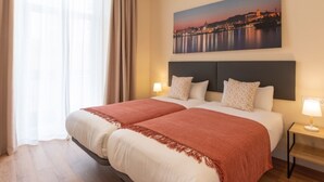 A hotel room with a large bed, two bedside tables, a nightstand, and a cityscape painting on the wall. - Coastal apartment in Málaga, near the beach, 2 bedrooms (Málaga)
