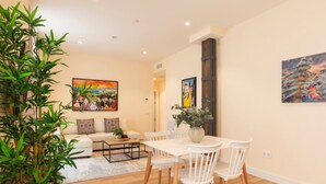 A modern living room with a dining area, featuring a sofa set, a coffee table, and a dining table with chairs. There are two paintings on the walls and a large potted plant in the corner. - Coastal apartment in Málaga, near the beach, 2 bedrooms (Málaga)