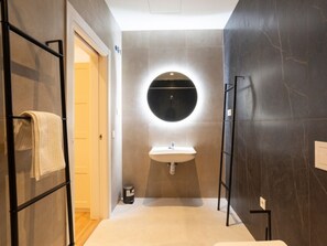 A modern bathroom with a round mirror, a sink, and a towel rack. - Beachfront apartment in Málaga, perfect for families and couples (Málaga)