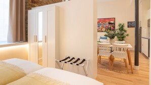 Ett modernt hotellrum med ett träpanelat tak, en säng med vita sängkläder, ett litet bord med stolar och en tavla på väggen.