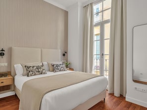 A bedroom with a large bed, a nightstand, a wall-mounted lamp, and a window with curtains. - Modern apartment in Malaga's center with Wi-Fi (Málaga)