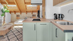 Eine moderne Küche mit Dachfenster, eine Essecke mit Sofa und Tisch sowie eine kleine Pflanze.