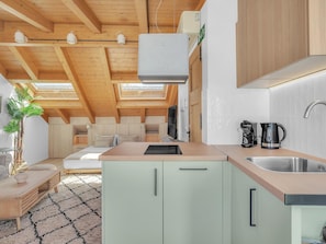 A modern kitchen with a skylight, a dining area with a sofa and table, and a small plant. - Modern Studio in the Heart of Malaga's Old Town (Málaga)