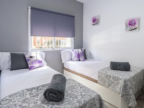 A room with two beds, a window with a blind, and two wall-mounted flower paintings. - Modern Apartment near Malaga Beaches (Málaga)