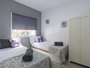 Une chambre avec deux lits, une armoire et une fenêtre avec un store.