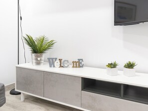 A modern living room with a white TV stand, a potted plant, and decorative letters spelling 'Welcome'. - Modern Apartment near Malaga Beaches (Málaga)