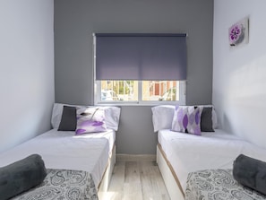 A room with two single beds, a window with a blind, and a small wall decoration. - Modern Apartment near Malaga Beaches (Málaga)