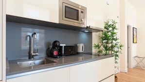 A modern kitchen with a built-in microwave, coffee maker, and kettle on the countertop. - Charming apartment near La Malagueta, Malaga (Málaga)