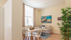 A modern living room with a dining area, a sofa, a coffee table, and a painting of a ship on the wall. - Charming apartment near La Malagueta, Malaga (Málaga)