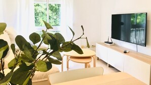 A modern living room with a sofa, a dining table, and a TV on a white cabinet. - Spacious apartment with balcony in Málaga (Málaga)