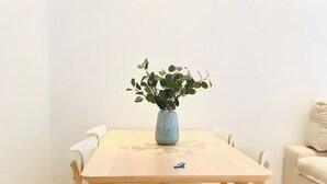 A wooden dining table with a vase of green plants, surrounded by white chairs. - Spacious apartment with balcony in Málaga (Málaga)
