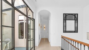 A hallway with a glass door leading to a dining area, a wooden staircase, and a white wall with a framed picture. - Exclusive Stay in Malaga with Wi-Fi and Air Conditioning Near Beach (Málaga)