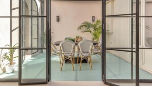 An open glass door leading to a patio with a table and chairs, surrounded by potted plants. - Exclusive Stay in Malaga with Wi-Fi and Air Conditioning Near Beach (Málaga)