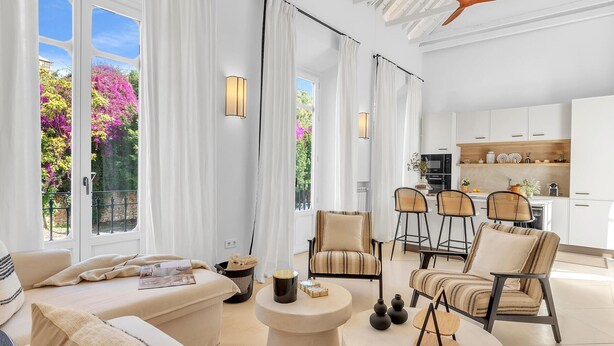 A modern living room with a sofa, chairs, and a coffee table. There is a kitchen in the background with white cabinets and a dining area. - Exclusive Stay in Malaga with Wi-Fi and Air Conditioning Near Beach (Málaga)