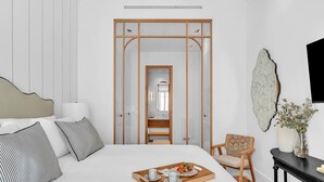 A modern bedroom with a large bed, a wooden wardrobe, a bedside table with a vase, and a chair. - Exclusive Stay in Malaga with Wi-Fi and Air Conditioning Near Beach (Málaga)