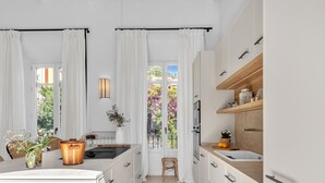 A modern kitchen with white cabinetry, a central island, and a view of a garden through large windows. - Exclusive Stay in Malaga with Wi-Fi and Air Conditioning Near Beach (Málaga)