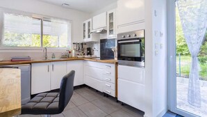 A modern kitchen with white cabinets, a black oven, and a window with a view of greenery. - Nice home in Saint-Yvi with WiFi (Saint-Yvi)