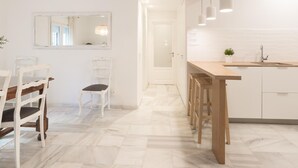 Eine moderne Küche mit einer Holzausziehtheke, weißen Schränken und Pendelleuchten.