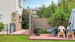A backyard with a stone wall, a wooden gate, and a small patio area with outdoor furniture. - 3 bedroom amazing home in Cancale (Cancale)