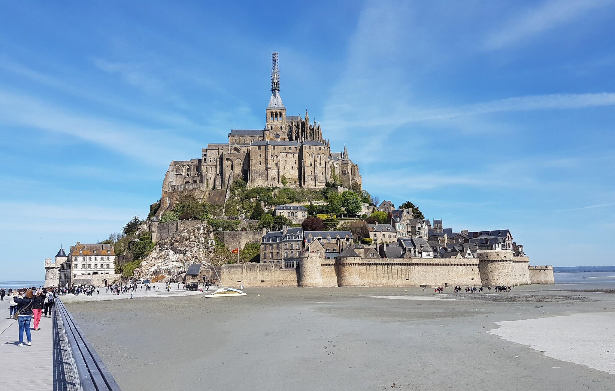 Un château historique, doté d’une tour imposante, situé sur une colline et offrant une vue sur une plage en contrebas.