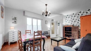 A living room with a dining table, chairs, a sofa, a cabinet, and a chandelier. - 3 bedroom amazing home in Cancale (Cancale)