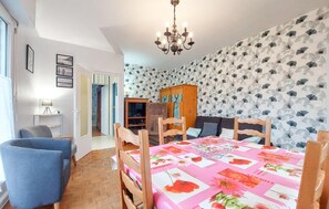 A dining area with a table set for four, a chandelier, and a patterned wallpaper. - 3 bedroom amazing home in Cancale (Cancale)