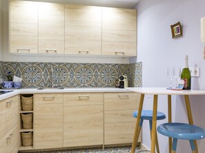 A kitchen with wooden cabinets, a patterned backsplash, and a small bar area with stools. - Charming Apt in the heart of Malaga with rooftop pool (Málaga)