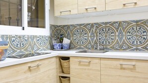 A kitchen with light wood cabinets, a white countertop, and patterned tile backsplash. - Charming Apt in the heart of Malaga with rooftop pool (Málaga)