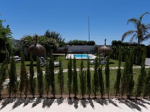 A pool area with lounge chairs, a thatched umbrella, and a clear blue sky. - Bright apartment, shared pool, beach access (Chilches)