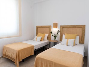 A hotel room with two single beds, each with a wooden headboard and a bedside table. - Bright apartment, shared pool, beach access (Chilches)