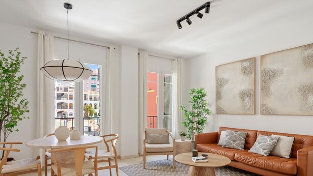Una sala moderna con una mesa de centro redonda de madera, un sofá de cuero, un área de comedor con una mesa y sillas redondas, y ventanas grandes con cortinas.