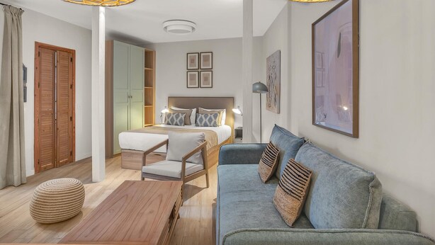 Een moderne slaapkamer met een bed, een slaapbank en een houten salontafel.